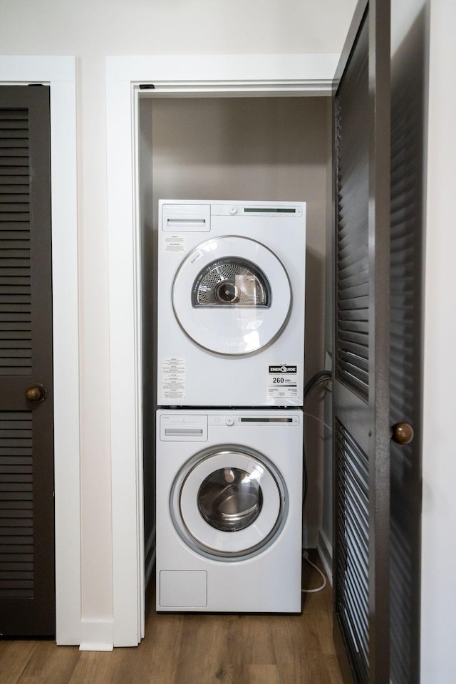 clothes washing area with stacked washer / drying machine and dark hardwood / wood-style floors