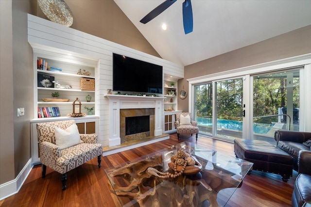 living room featuring ceiling fan, built in features, high vaulted ceiling, wood-type flooring, and a fireplace