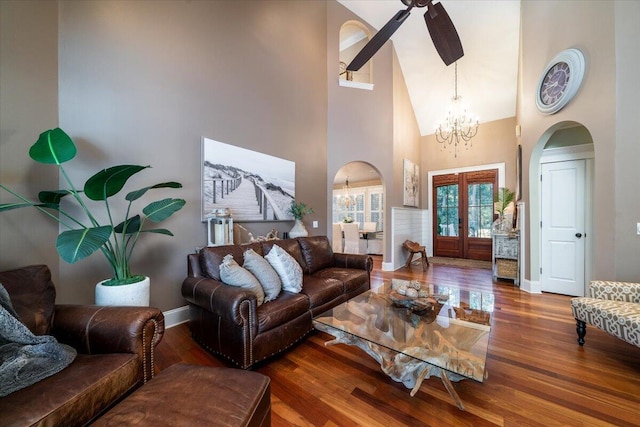 living room featuring hardwood / wood-style flooring, ceiling fan with notable chandelier, a towering ceiling, and french doors