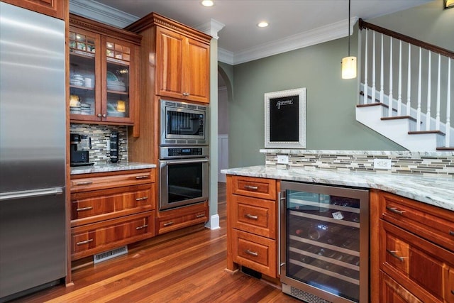 kitchen with tasteful backsplash, light stone counters, crown molding, built in appliances, and wine cooler