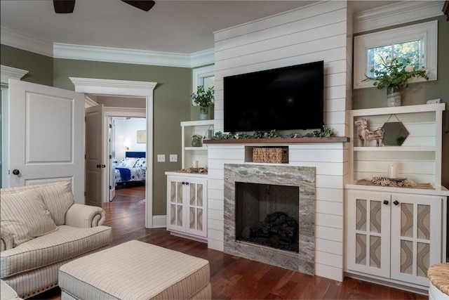 living room featuring dark hardwood / wood-style floors, ceiling fan, crown molding, and a premium fireplace