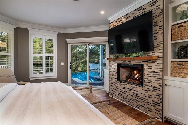 bedroom with access to exterior, dark hardwood / wood-style floors, a stone fireplace, and crown molding