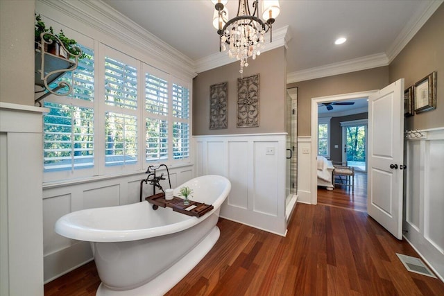 bathroom with plenty of natural light, wood-type flooring, ornamental molding, and an inviting chandelier