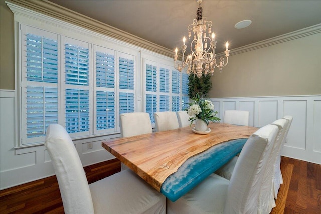 dining area featuring dark wood-type flooring, ornamental molding, and a notable chandelier