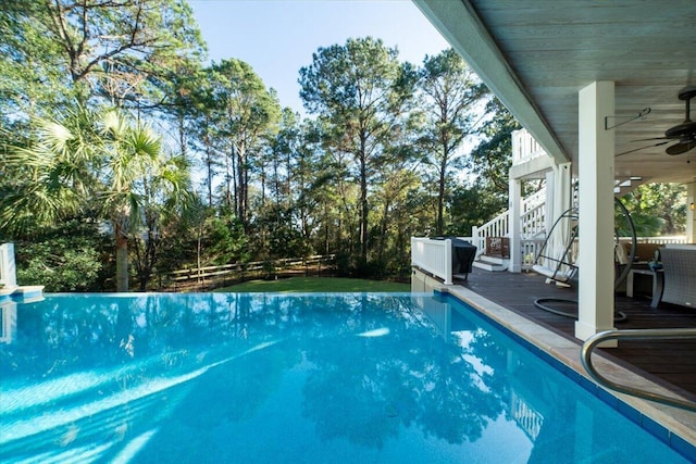 view of swimming pool featuring ceiling fan and a deck