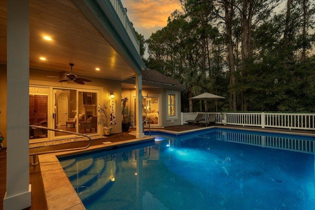 pool at dusk featuring ceiling fan