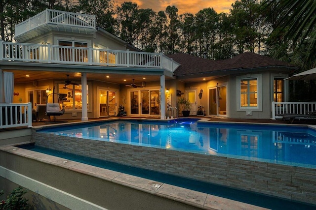 pool at dusk featuring ceiling fan