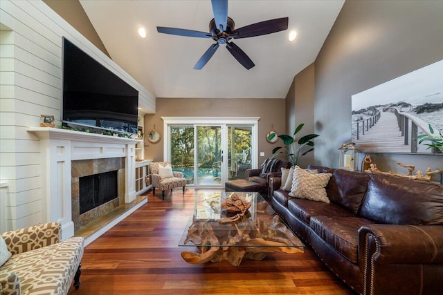 living room with dark hardwood / wood-style flooring, ceiling fan, a fireplace, and lofted ceiling