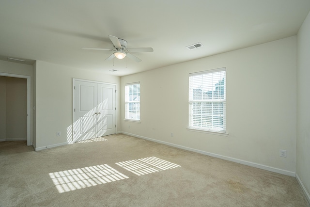 unfurnished bedroom with light colored carpet, ceiling fan, and a closet