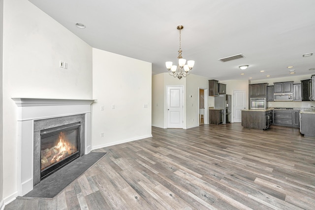 unfurnished living room featuring an inviting chandelier and hardwood / wood-style floors