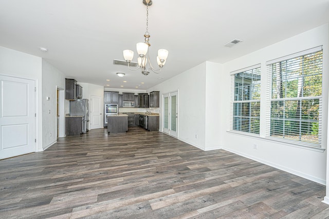 unfurnished living room featuring dark wood-type flooring and a notable chandelier