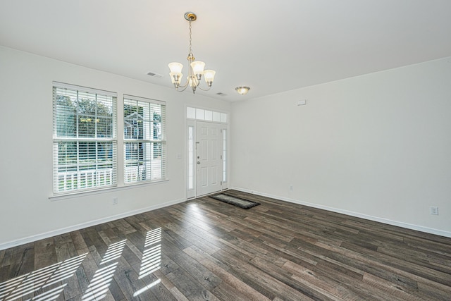 empty room featuring dark hardwood / wood-style flooring and a notable chandelier