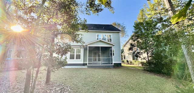 rear view of house featuring a sunroom and a yard