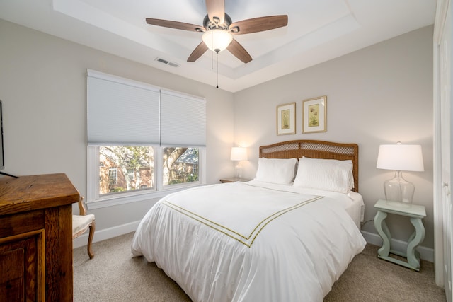 bedroom with ceiling fan, a raised ceiling, and light carpet