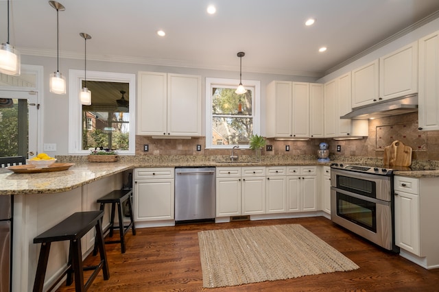 kitchen featuring appliances with stainless steel finishes, a breakfast bar area, white cabinets, and a wealth of natural light