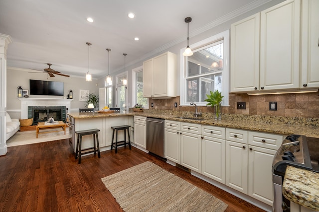 kitchen featuring kitchen peninsula, white cabinets, hanging light fixtures, appliances with stainless steel finishes, and dark wood-type flooring