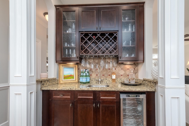 bar featuring light stone countertops, sink, decorative backsplash, beverage cooler, and ornamental molding