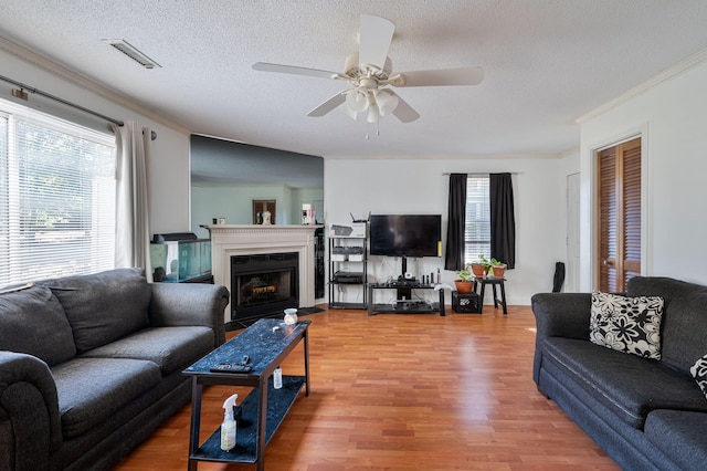 living room with ornamental molding, a textured ceiling, hardwood / wood-style flooring, and ceiling fan