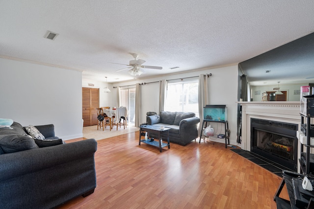 living room with ceiling fan, crown molding, a textured ceiling, and hardwood / wood-style floors