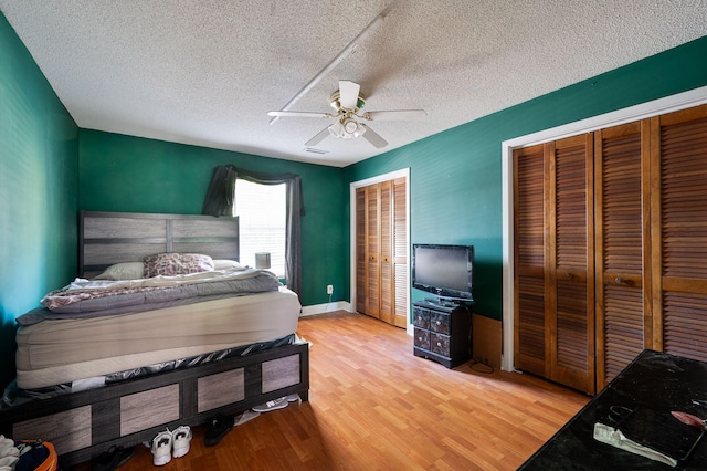 bedroom featuring a textured ceiling, two closets, wood-type flooring, and ceiling fan