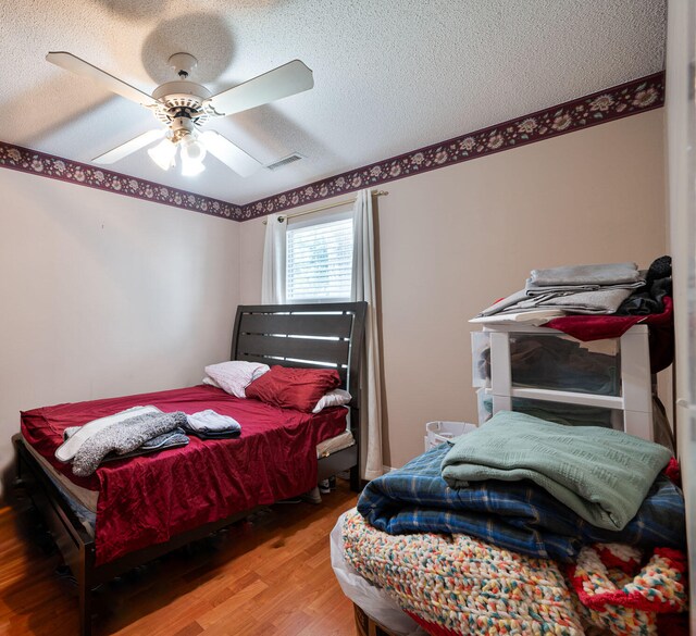 bedroom with ceiling fan, a textured ceiling, and hardwood / wood-style floors