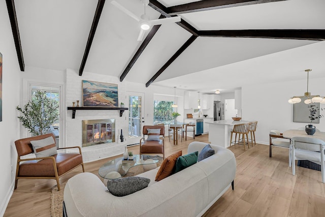 living room with an inviting chandelier, plenty of natural light, a fireplace, and light wood-type flooring