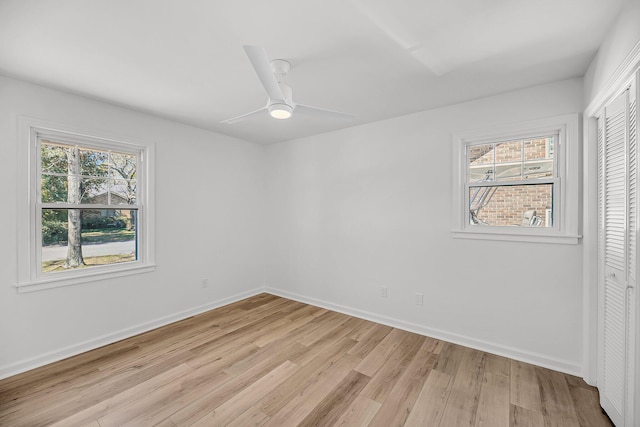 empty room featuring ceiling fan, a healthy amount of sunlight, light wood-type flooring, and baseboards