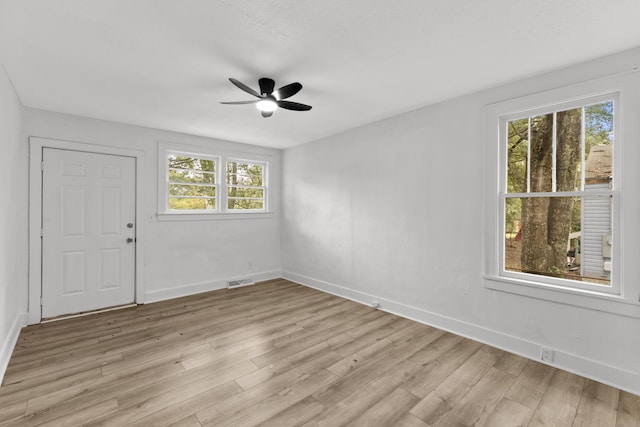 spare room featuring ceiling fan, light hardwood / wood-style flooring, and a healthy amount of sunlight