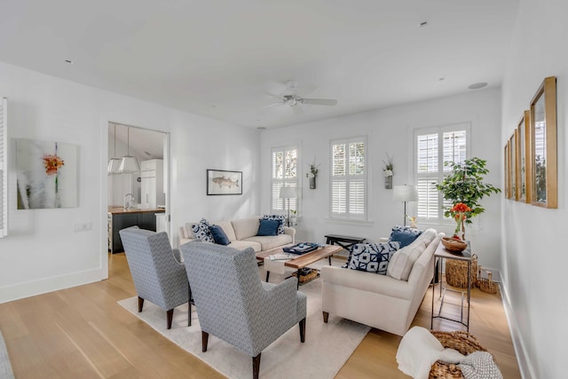 living room featuring ceiling fan, sink, and light hardwood / wood-style flooring