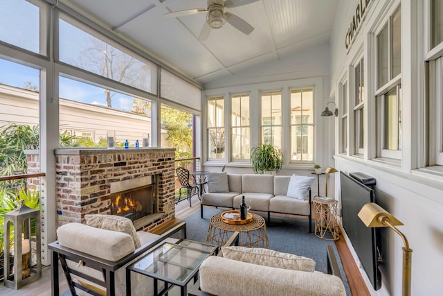 sunroom / solarium with vaulted ceiling, a brick fireplace, and ceiling fan