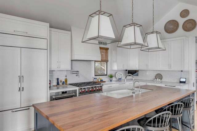 kitchen featuring vaulted ceiling, white cabinetry, premium appliances, and a center island with sink