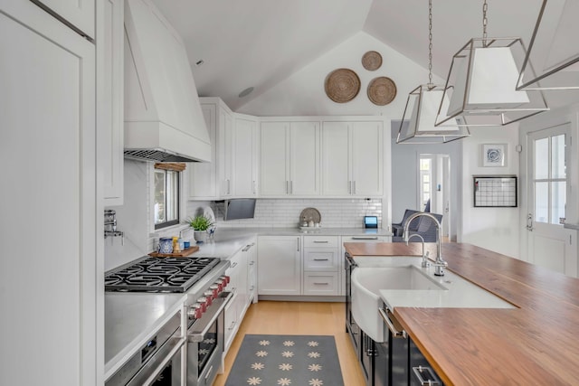 kitchen with custom exhaust hood, white cabinets, and decorative light fixtures