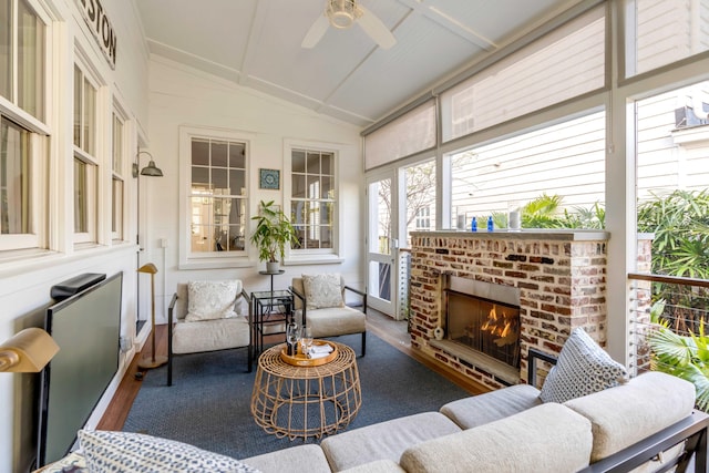 sunroom with a brick fireplace, ceiling fan, and vaulted ceiling