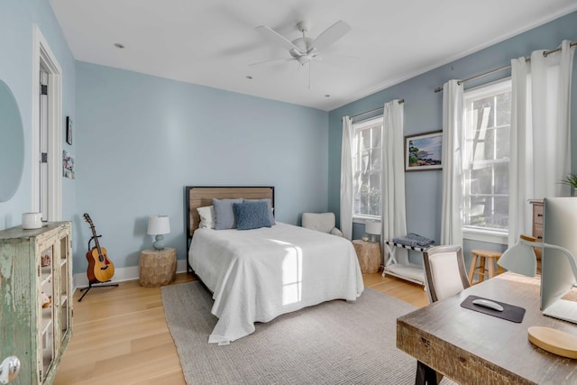 bedroom featuring ceiling fan, multiple windows, and light wood-type flooring