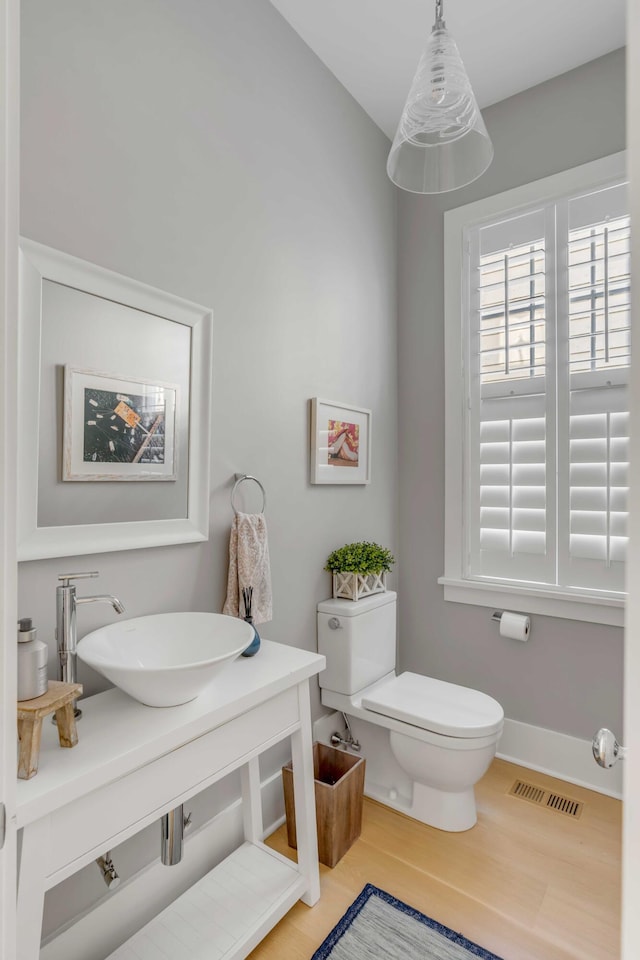 bathroom with toilet, wood-type flooring, and sink