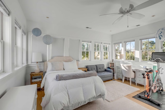 bedroom with ceiling fan, light hardwood / wood-style floors, and multiple windows