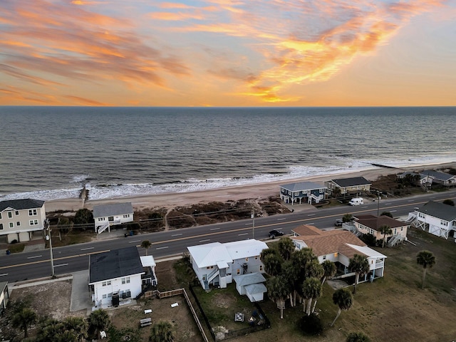 aerial view at dusk with a water view and a view of the beach