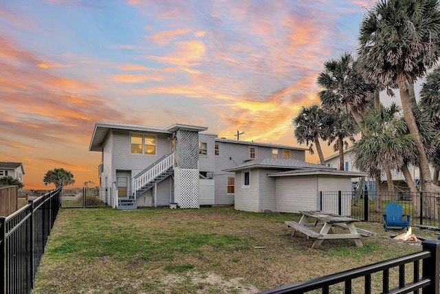 back house at dusk featuring an outdoor fire pit and a lawn