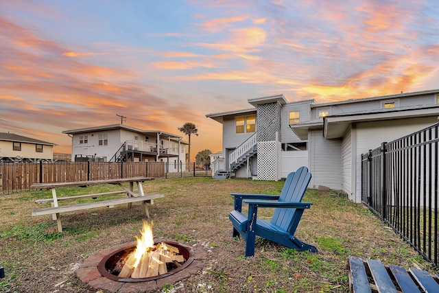 back house at dusk with a yard and a fire pit