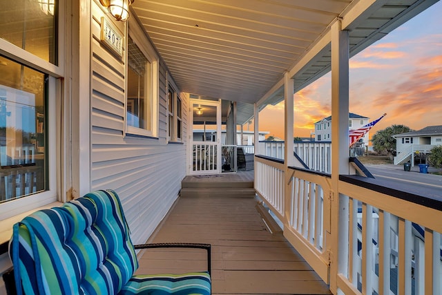 deck at dusk featuring covered porch