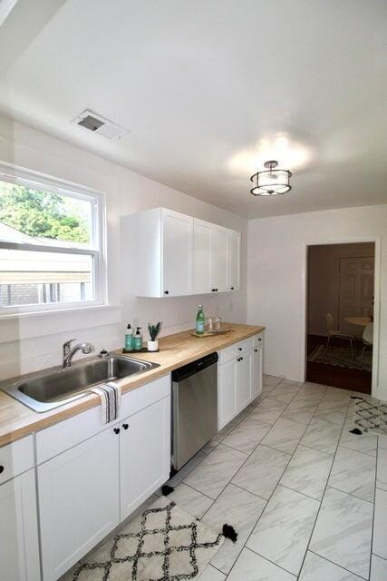 kitchen featuring butcher block counters, dishwasher, white cabinets, and sink