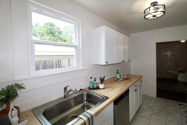 kitchen featuring butcher block countertops, dishwasher, white cabinetry, and sink