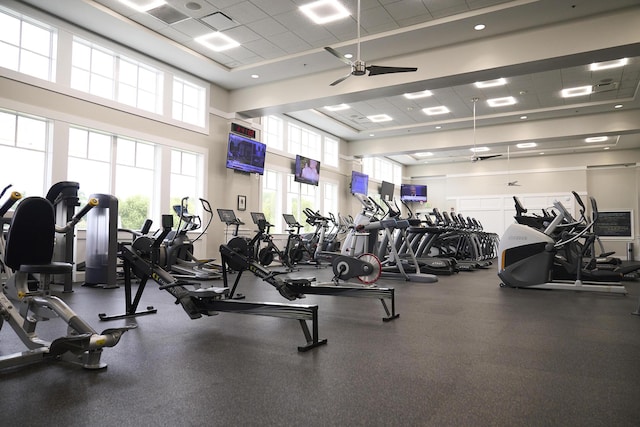 exercise room with a wealth of natural light, ceiling fan, and a high ceiling