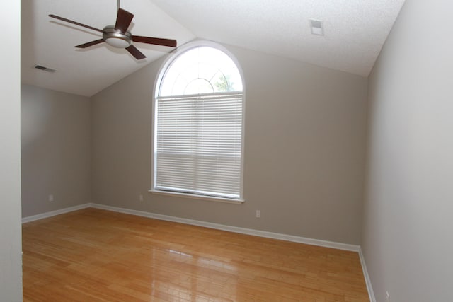 unfurnished room with ceiling fan, a textured ceiling, vaulted ceiling, and light wood-type flooring