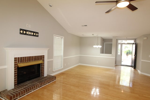 unfurnished living room with a brick fireplace, hardwood / wood-style floors, ceiling fan, and vaulted ceiling