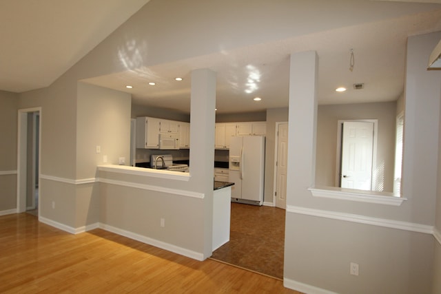 kitchen featuring light hardwood / wood-style flooring, white cabinets, kitchen peninsula, and white appliances