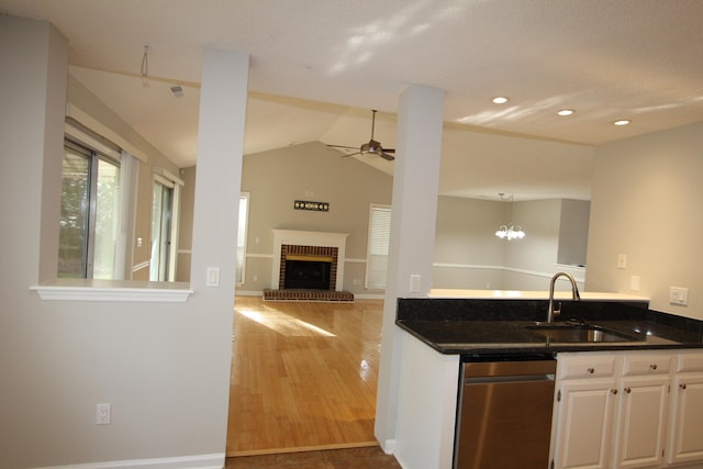 kitchen featuring wood-type flooring, sink, vaulted ceiling, white cabinets, and a fireplace