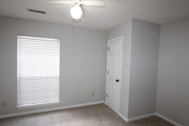 unfurnished room with ceiling fan, a textured ceiling, and carpet flooring