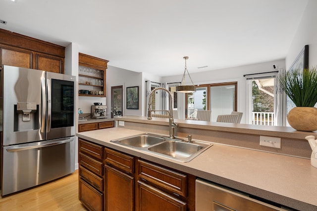 kitchen with pendant lighting, sink, light hardwood / wood-style flooring, and appliances with stainless steel finishes