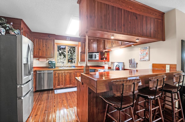 kitchen featuring light hardwood / wood-style floors, a breakfast bar, kitchen peninsula, sink, and stainless steel appliances